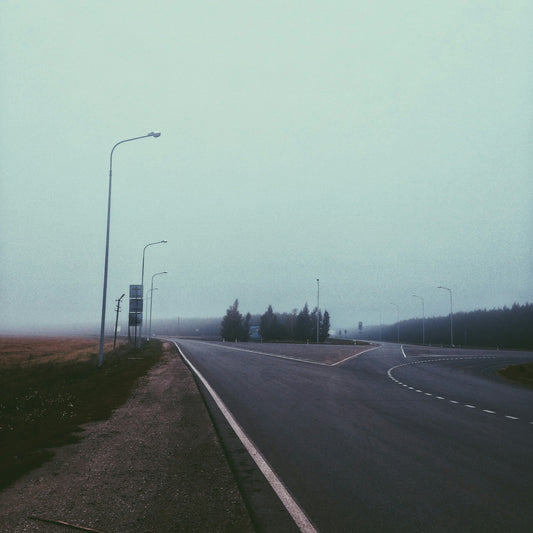 a foggy road in the middle of a rural area