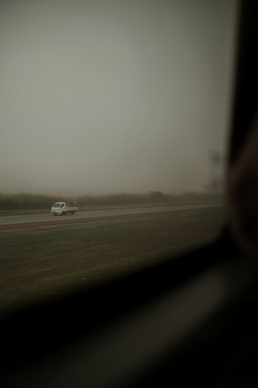 White truck driving on a foggy road.