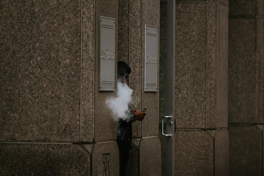 Person beim Vapen vor Gebäude, erkundet unvergessliche Duftreiseziele weltweit mit grünem Tee
